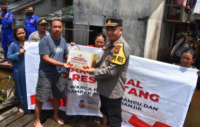 Kapolres Sintang, AKBP Ventie Bernard Musak, menyalurkan bantuan berupa paket sembako kepada warga terdampak banjir. Foto: Kris/Istimewa