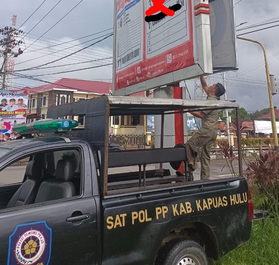 Petugas Satpol PP menurunkan APK yang terpasang di Kota Putussibau, Senin (12/2/2024). Foto: Taufiq AS/Jurnalis.co.id