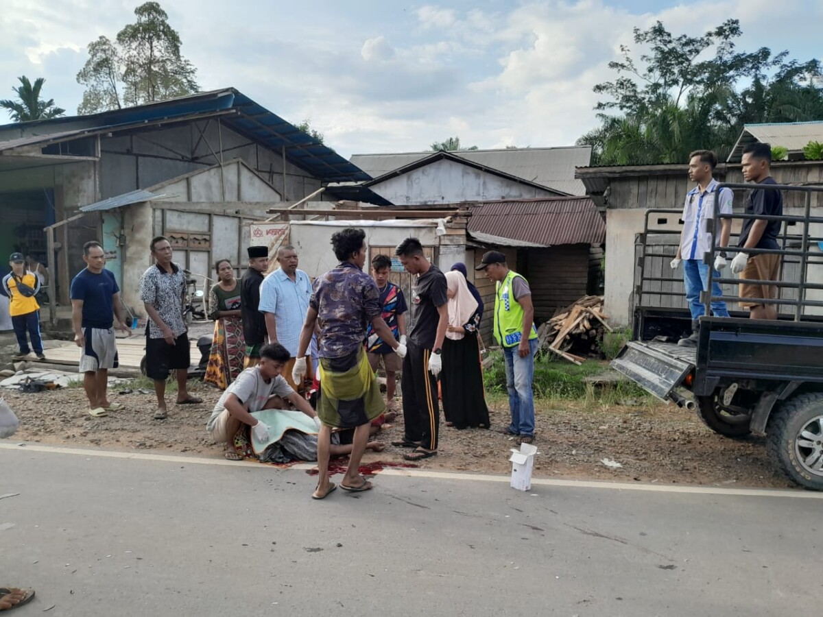 Warga saat mengangkat Jenazah pemotor yang tergeletak di badan jalan.