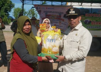 Pj Bupati Mempawah Ismail saat menyerahkan beras, salah satu pangan murah yang dijual kepada warga pembeli. - Foto, Bayu Humas Protokol