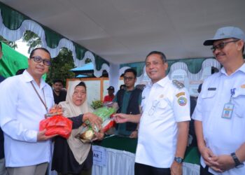 Caption Foto : Pj Wali Kota Pontianak Edi Suryanto menyerahkan secara simbolis paket kebutuhan pokok kepada Tukinem yang berbelanja di Operasi Pasar Murah ,Pontianak Timur. Foto : Diskominfo