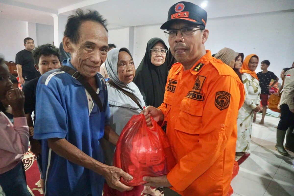 Pj Bupati Mempawah Ismail saat menyerahkan bantuan kepada warga yang mengungsi akibat terdampak banjir di Wisma Candramidi Mempawah