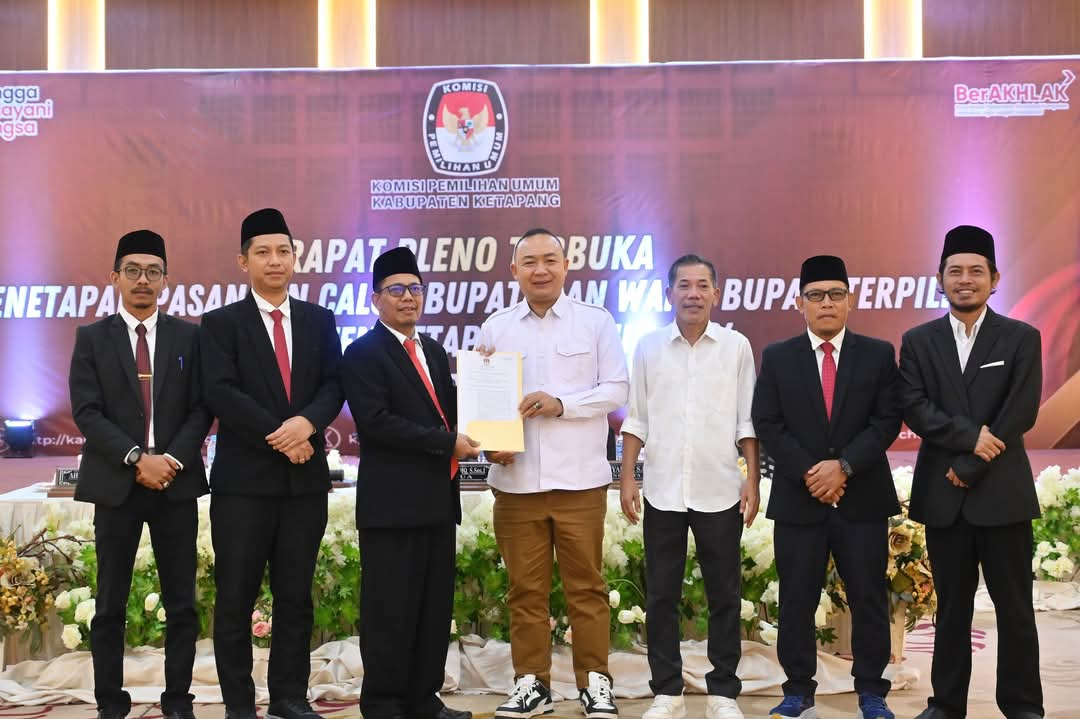 Caption: Ketua KPU Kabupaten Ketapang, Ahmad Sidiq, menyerahkan salinan keputusan penetapan kepada Bupati Ketapang terpilih, Alexander Wilyo, dan Jamhuri Amir, periode 2025-2030, Kamis (09/01/2025).