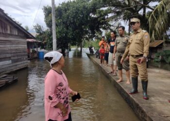 Penjabat PJ Bupati Alfian Salam didampingi BPBD Kayong Utara saat meninjau lokasi banjir di Desa Simpang Tiga dan Riam Berasap. Senin (20/1/2025). Foto (Porkopim)