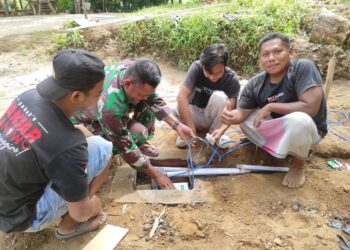 Ustadz Jazuli, paling kanan, saat membantu pemasangan pipa air bersih sumur bor. Foto:Sigit Priyono/Jurnalis.co.id