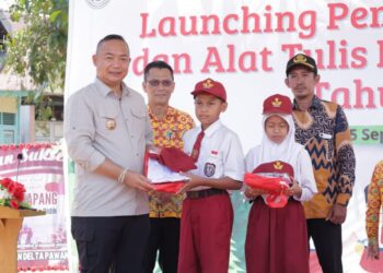 Bupati Ketapang, Alexander Wilyo saat menyerahkan seragam sekolah kepada salah satu siswa penerima manfaat, Kamis (25/09). Foto: JURNALIS.co.id / Abdul.