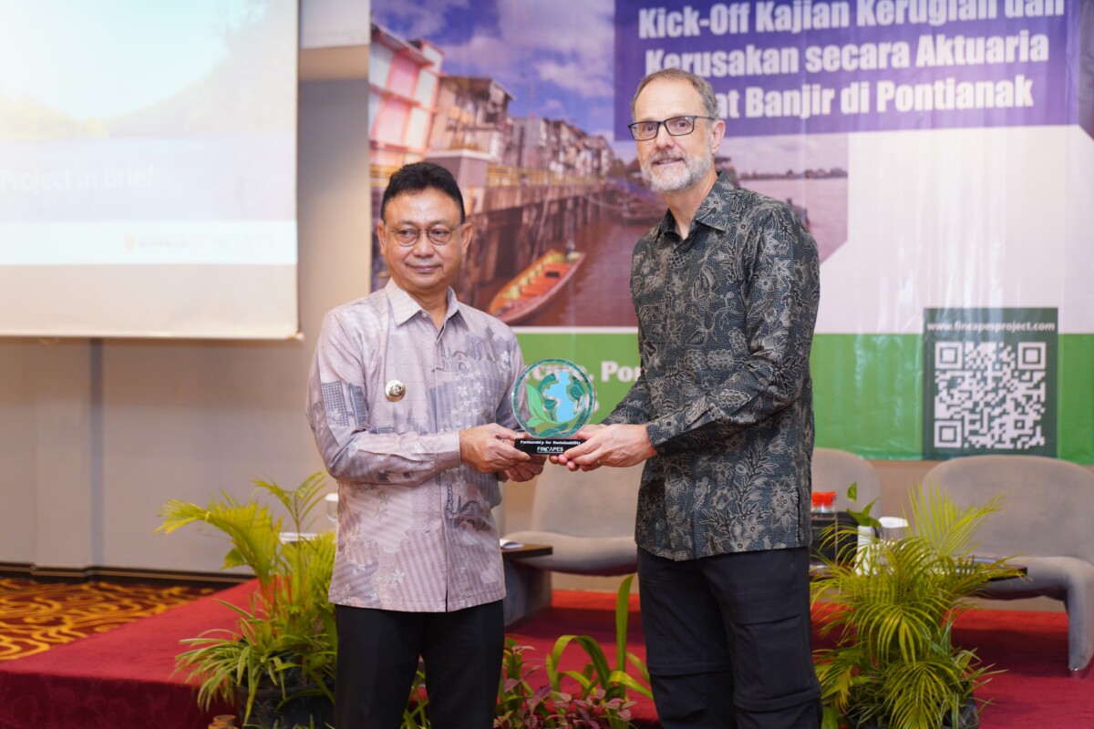 Wali Kota Pontianak, Edi Rusdi Kamtono menerima cinderamata kolaborasi dari perwakilan Universitas Waterloo Kanada, Prof. Stefan Steiner usai membuka Kick Off Kajian Kerugian dan Kerusakan secara Aktuaria Akibat Banjir di Pontianak, di Hotel Mercure, Kamis (15/01/2026).