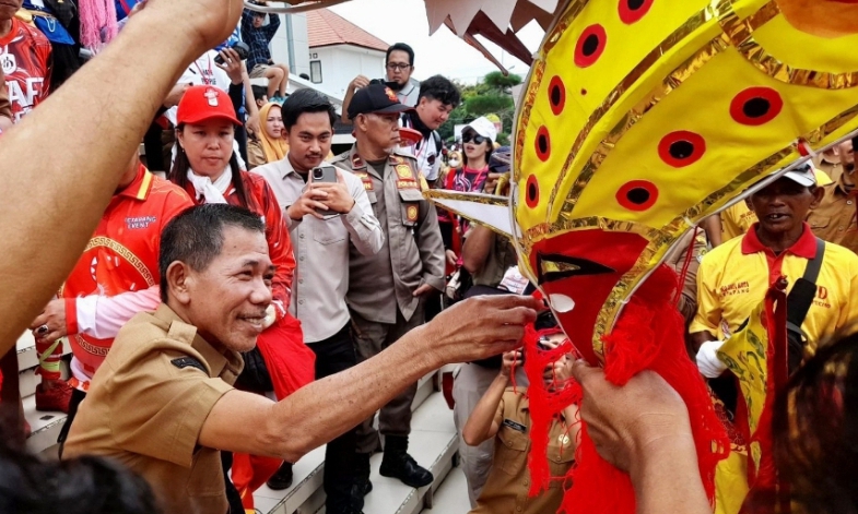 Wakil Bupati Ketapang, Jamhuri Amir menyerahkan angpao kepada naga saat arak-arakan Cap Go Meh, Senin (02/03/2026).(Foto: Prokopim Pemkab Ketapang).