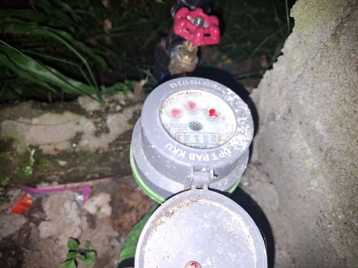 Penampakan meteran air yang di pasang UPT Air Bersih tak berfungsi dan terkesan mengambat saluran air ke rumah warga.