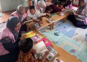 Srikandi PLN UIP3B Kalimantan ikut mengajari anak-anak membaca buku cerita.