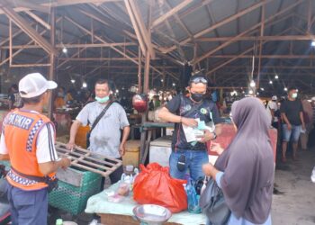 Anggota AJK saat menyerahkan masker ke salah satu pembeli di pasar H Sani. Foto: AJK.