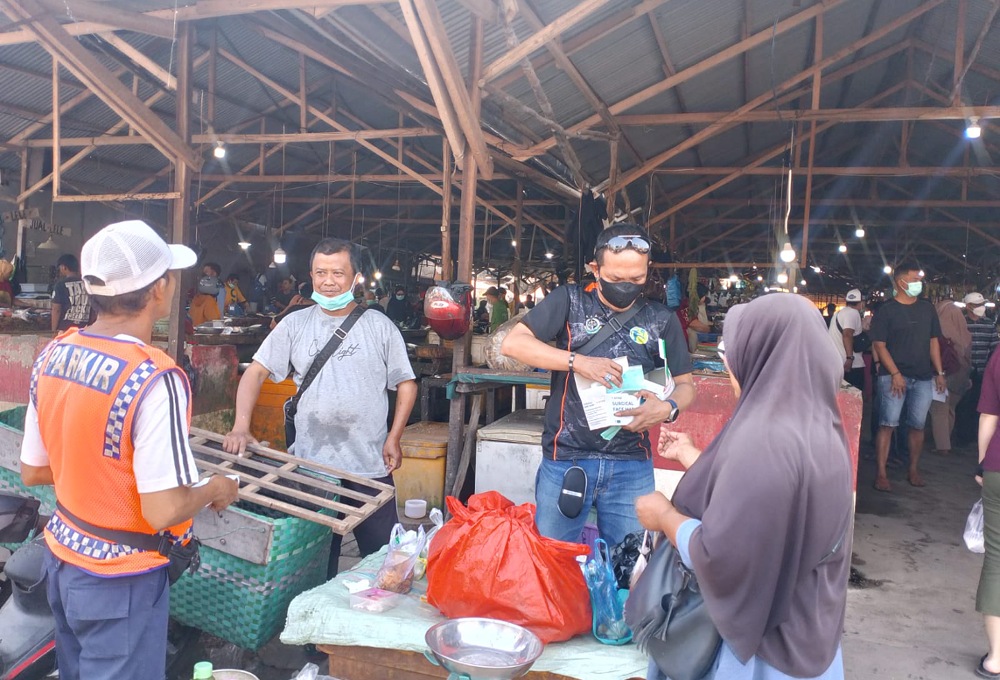 Anggota AJK saat menyerahkan masker ke salah satu pembeli di pasar H Sani. Foto: AJK.